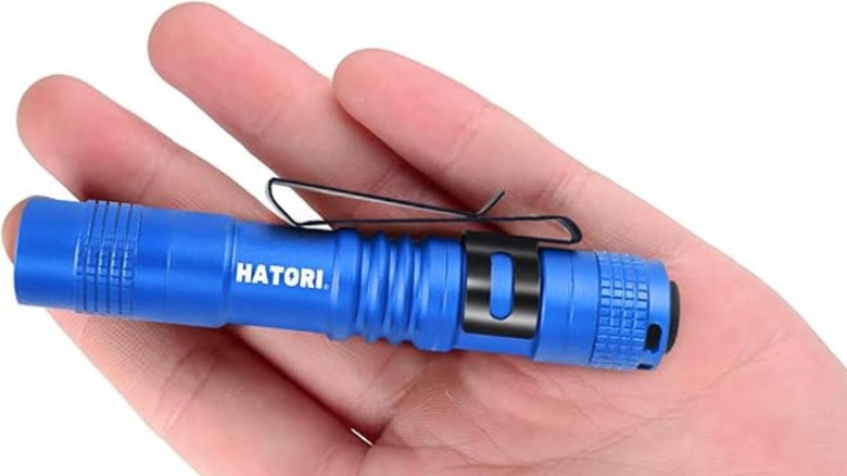 Hand holding small blue Hatori flashlight