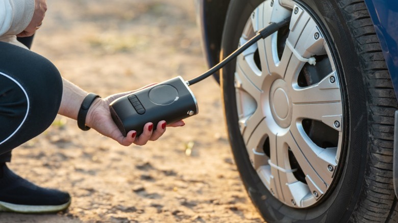 A person using a portable tire inflator