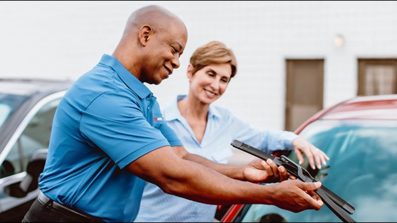 Two people replacing windshield wipers