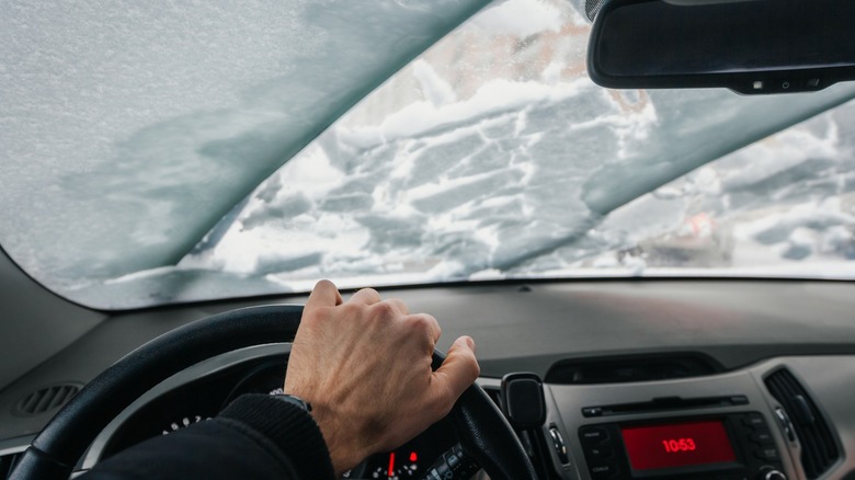 Interior view of snow covered windshield with wipers on