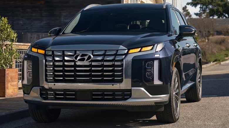 A black 2025 Hyundai Palisade parked next to a building.