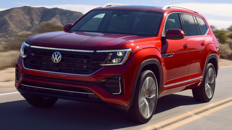 Volkswagen Atlas driving down a road with a mountain range and clear blue sky in the background