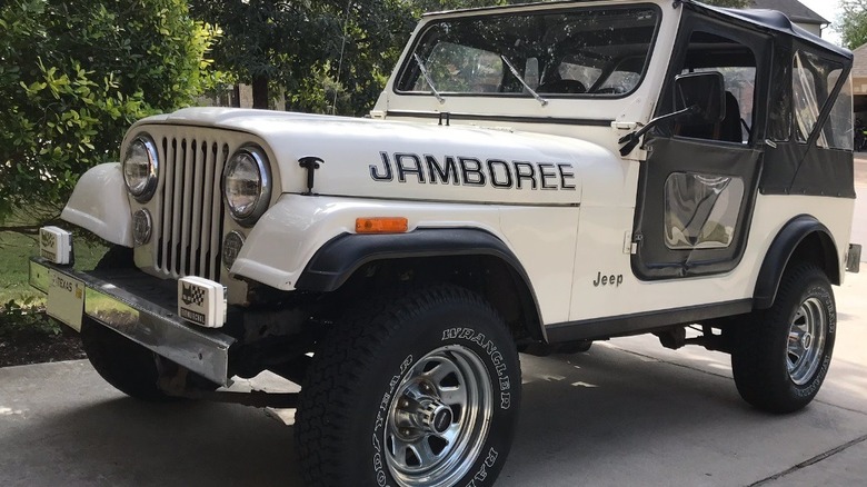 White Jeep CJ7 Jamboree edition with black soft top and doors parked in driveway