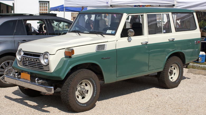 Green and white 1979 Toyota Land Cruiser FJ55 in parking lot with pop-up tent in background