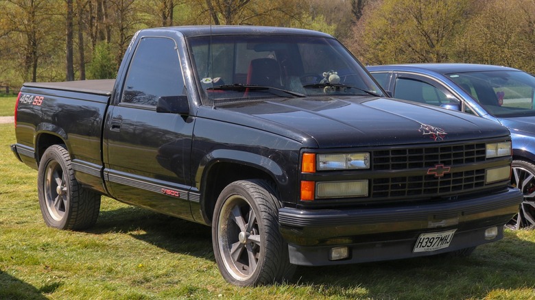 A black 1990 Chevrolet 454 SS pickup parked on grass.