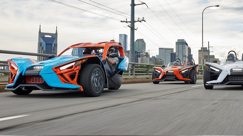 Three Polaris Slingshots driving