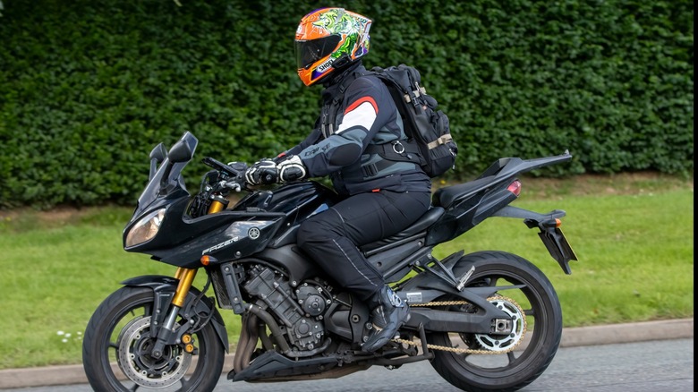 A rider with a patterned orange helmet takes a Yamaha Fazer for a spin.