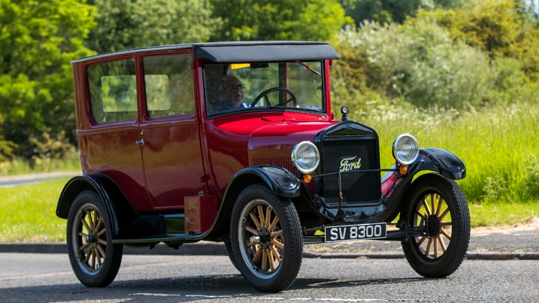 Red Model T Ford driving down country road