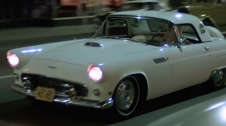 White Ford Thunderbird driving down street