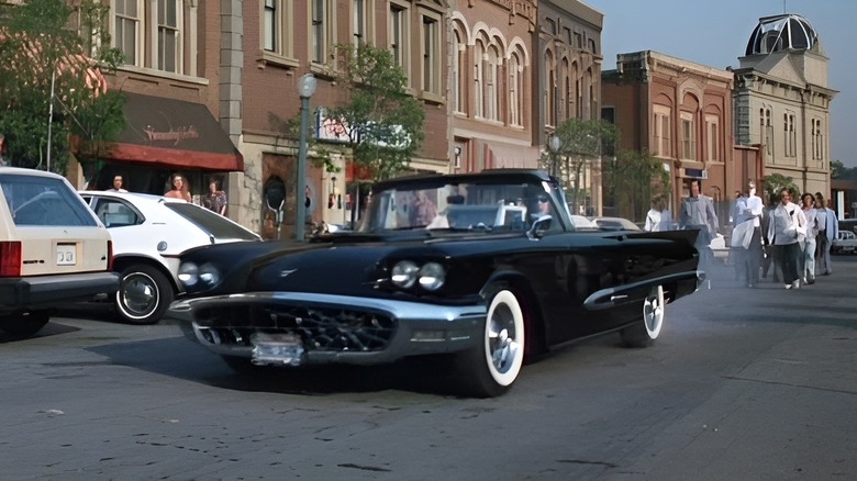 Elvira driving Thunderbird down town street