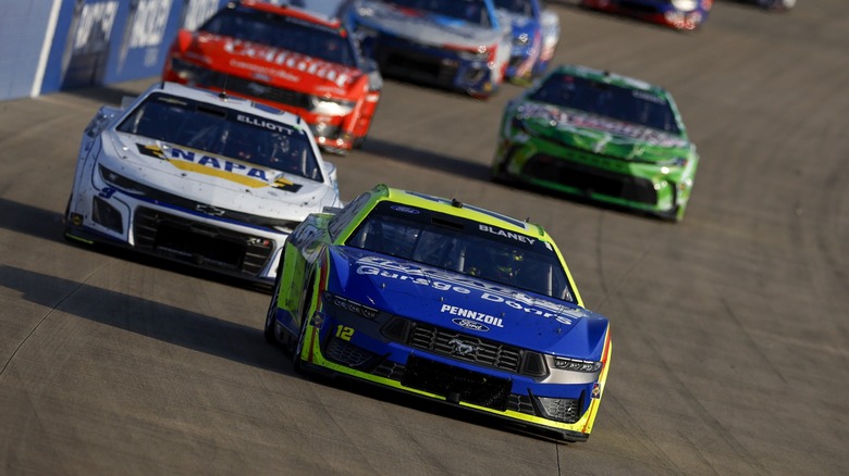 Ford mustang leading other race cars on a speedway