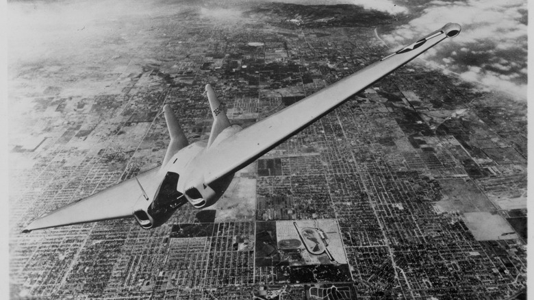 Grayscale photo of XP-79 flying over city