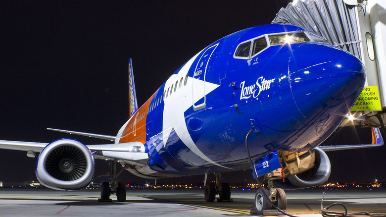 A Boeing 737 painted in Southwest's Lone Star One design, tucked up to a jetway.