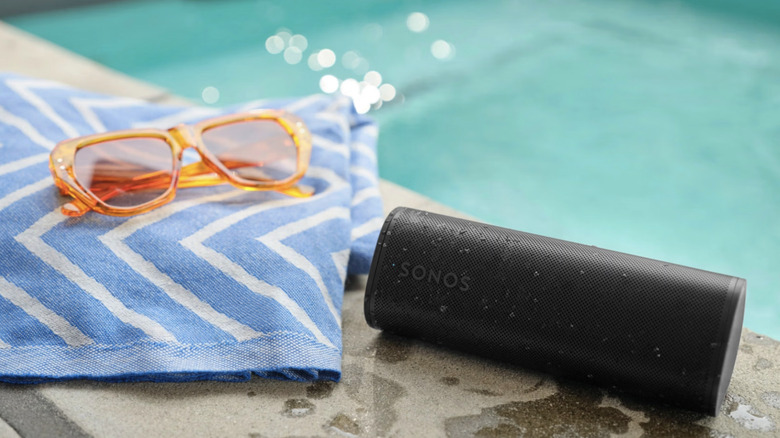 Sonos Roam 2 poolside with sunglasses and towel