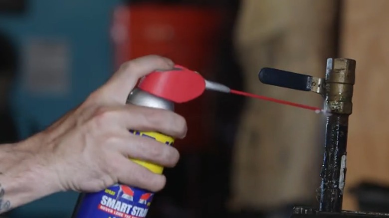 Person spraying WD-40 on threading