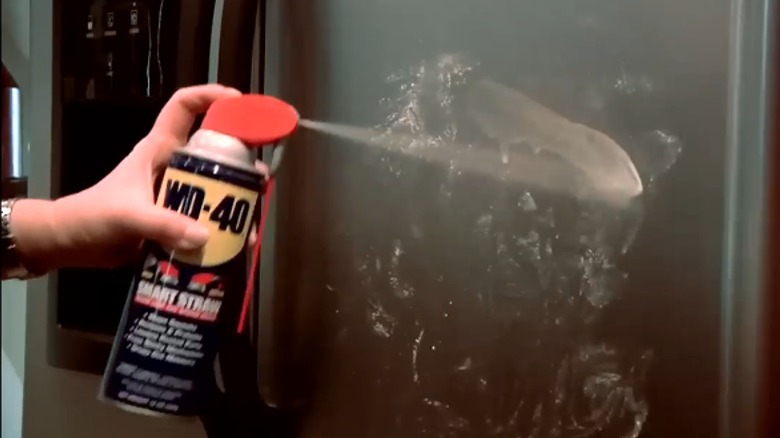 Person spraying WD-40 on fridge