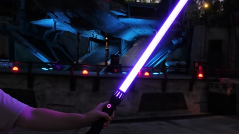 Person holding purple lightsaber in hanger deck