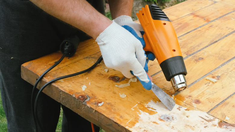 Person using a heat gun to remove a varnish