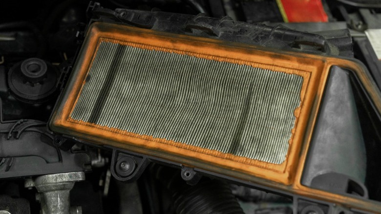 A dirty engine air filter sitting in an engine bay