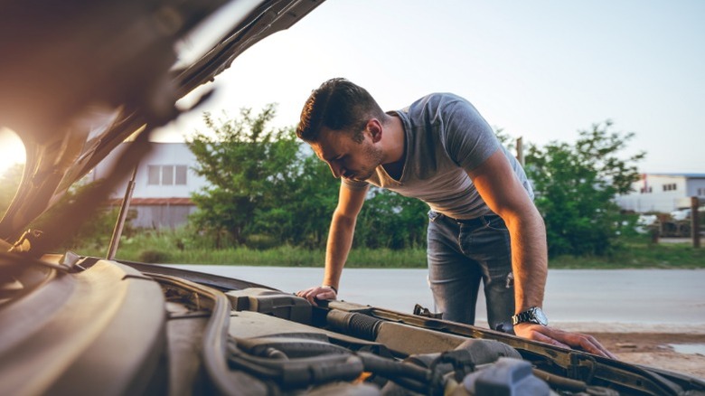 A person inspecting their car's engine