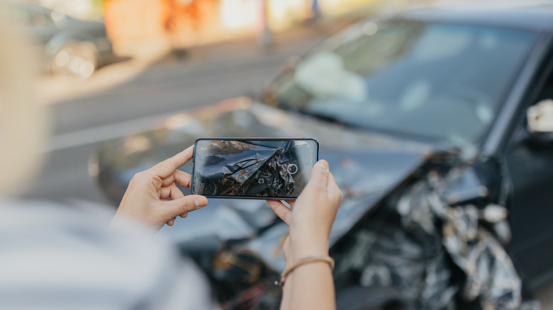 person taking a picture of a car after an accident