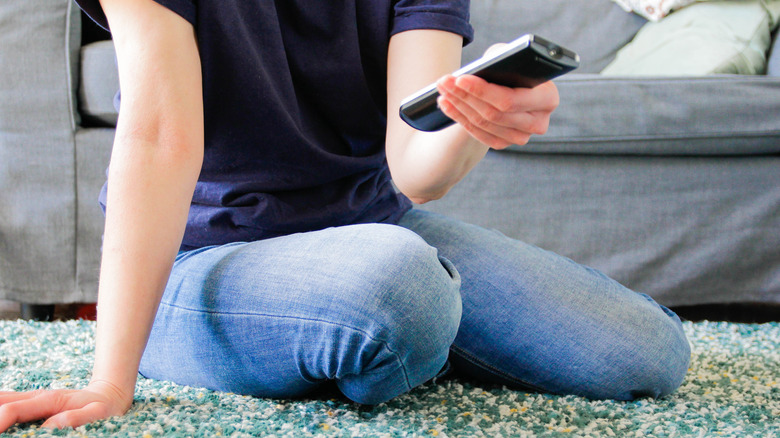 Woman sitting on floor holding TV remote