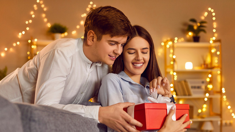 couple smiling while holding a red box