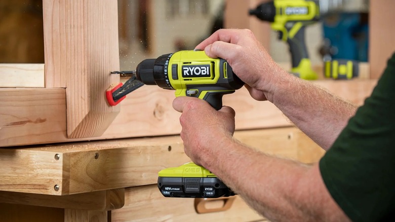 Pesron using a rypbi drill to drill a hole in a piece of wood