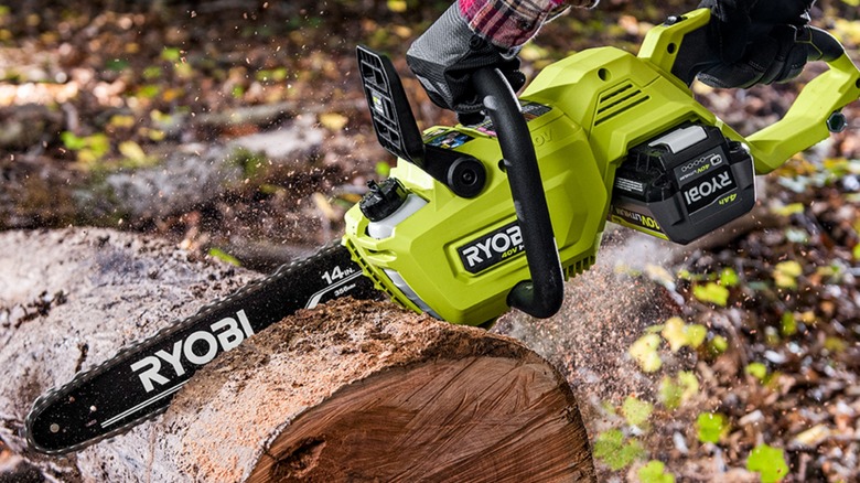 Man using Ryobi 40V Chainsaw to cut log