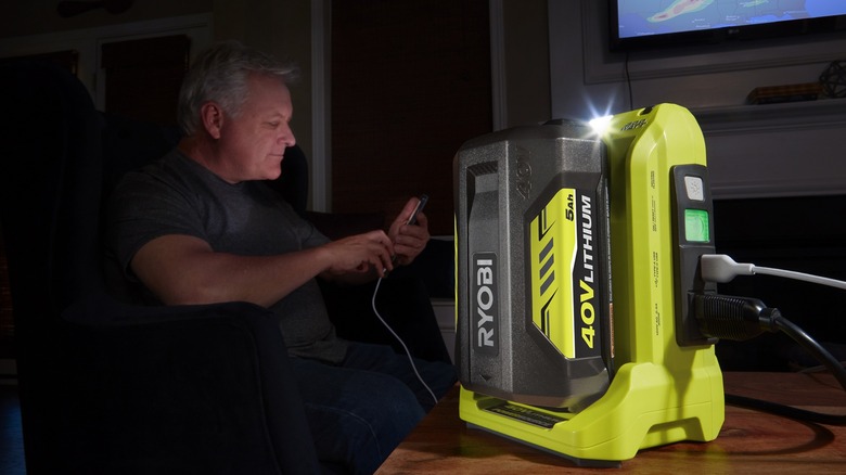 man looking at phone plugged into Ryobi 40v power source