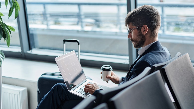 man using a Macbook in an airport