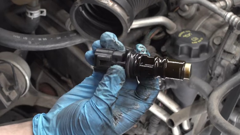 mechanic holding camshaft position sensor