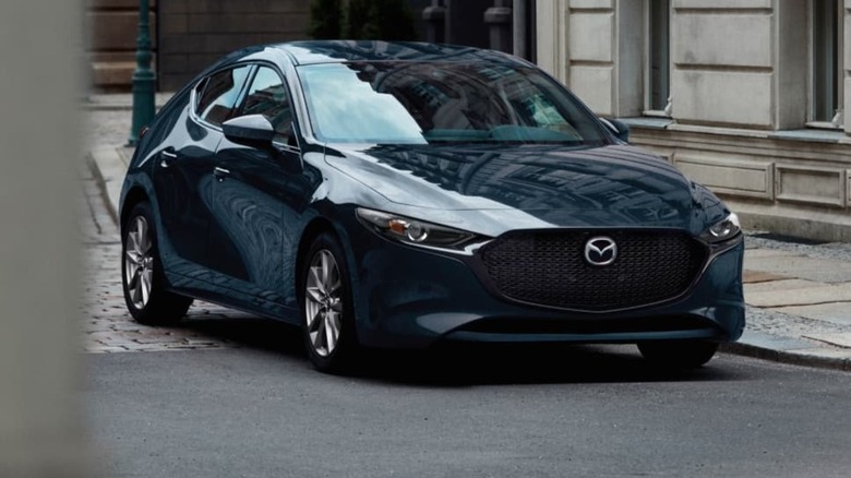 Mazda3 Hatchback parked a paved surface with buildings in the background