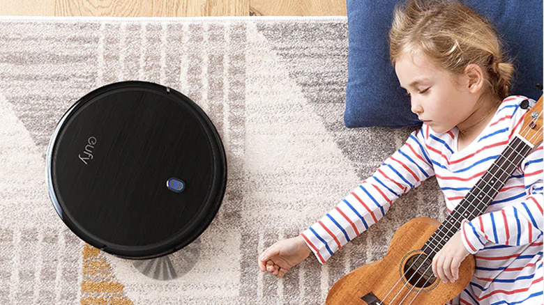 Eufy BoostIQ RoboVac 11S cleaning rug next to sleeping child