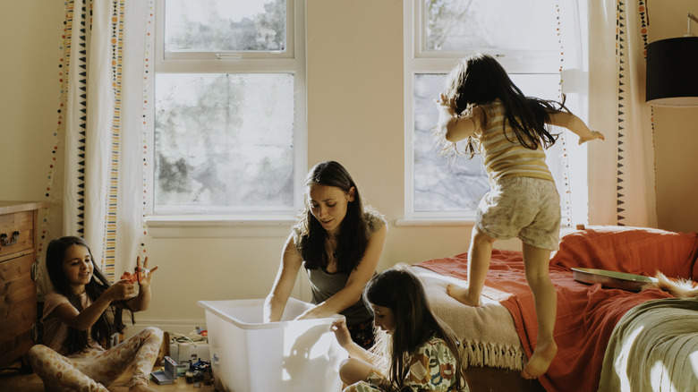 A mom playing with kids with toys on the ground