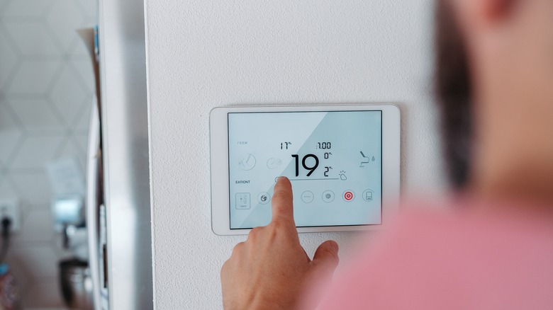 A man uses a smart display to access a smart thermostat.