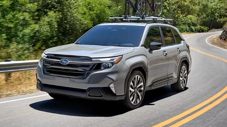 Silver Subaru Forester Touring driving on a winding road road next to trees