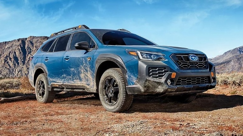 Blue Subaru Outback Wilderness parked off-road with blue sky in the background