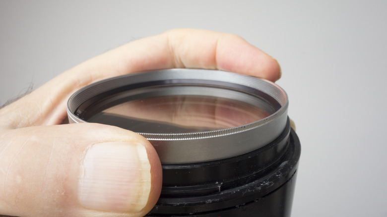 person holding camera lens filter