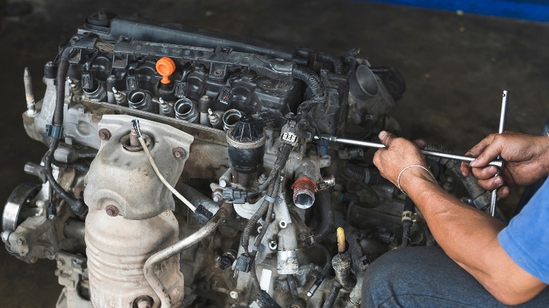 person working on an engine without the valve cover