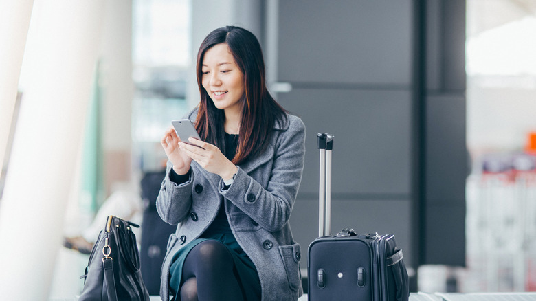 woman with luggage using phone