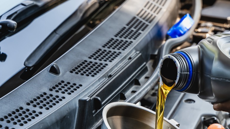 Person pouring oil into the car