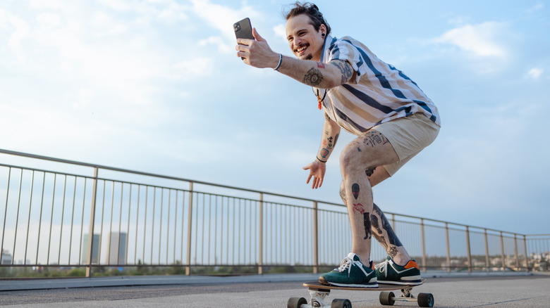 man filming on iPhone while skateboarding