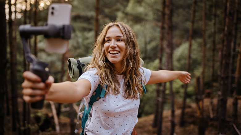 woman using smart phone to vlog in the wilderness