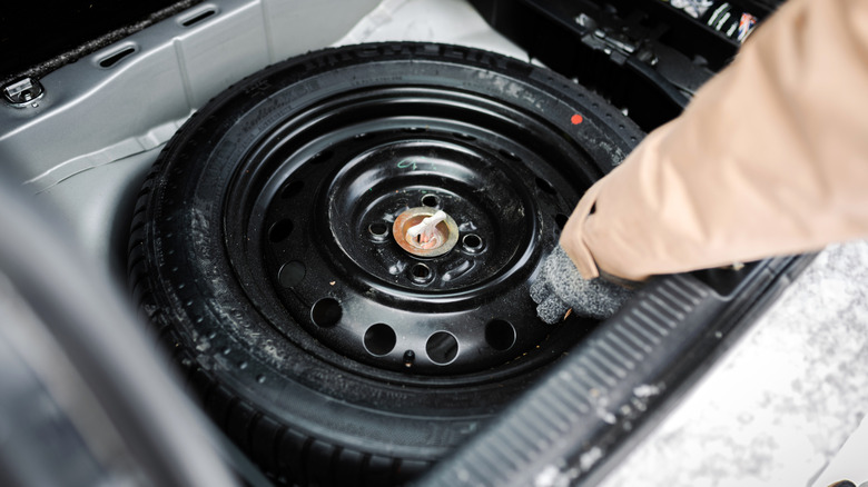 Person taking out donut tire from trunk