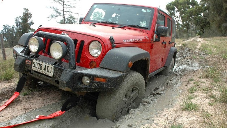 red Jeep being pulled by tow strap