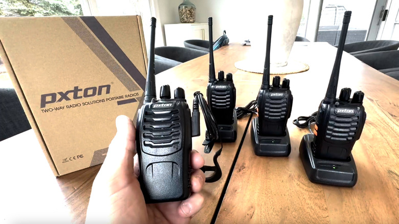 Walkie talkies sitting on a table with someone holding one