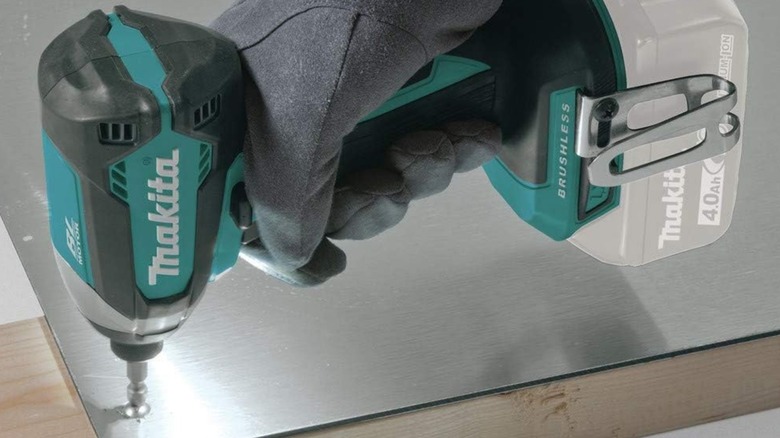 A person using an 18-volt Makita impact driver with a screwdriver bit attached