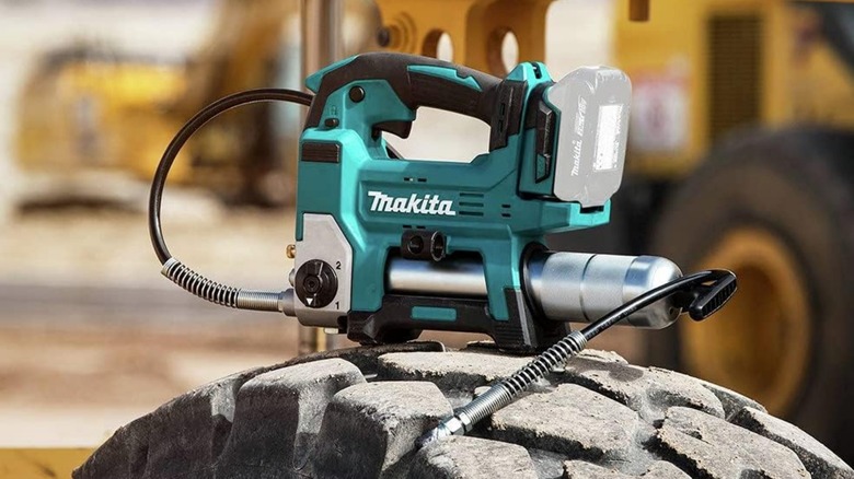 A Makita 18-volt grease gun sitting on a tire