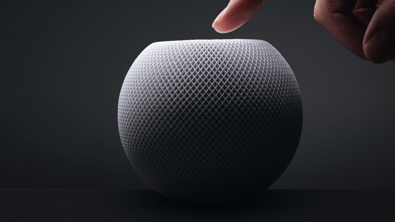 person pressing a Apple HomePod mini speaker